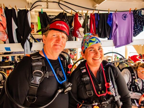 Two people in scuba gear standing next to each other.