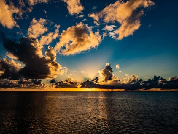 A sunset over the ocean with clouds in the sky.