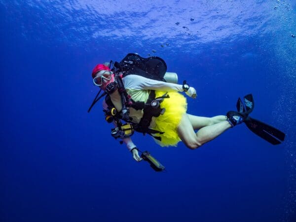 A scuba diver in yellow and red is swimming.