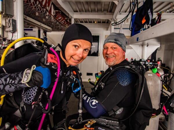 A man and woman in scuba gear smile for the camera.