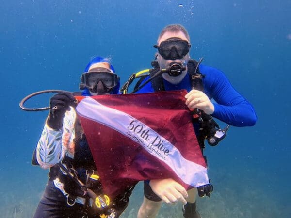 Two people holding a dive flag underwater