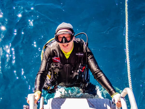 A man in scuba gear is sitting on the boat.