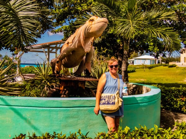 A woman standing next to a statue of an alligator.