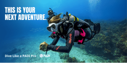 A scuba diver is in the water with his hands on his chest.