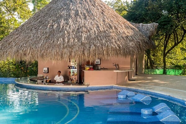 A man sitting in front of an outdoor tiki bar.