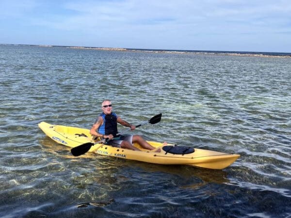 A man in a yellow kayak on the water.