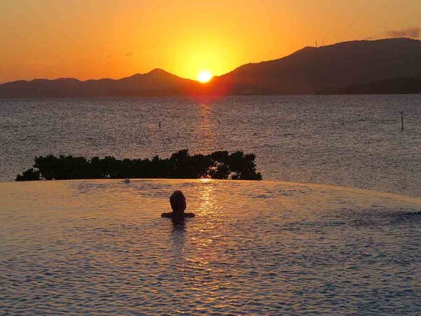 A person swimming in the water at sunset.