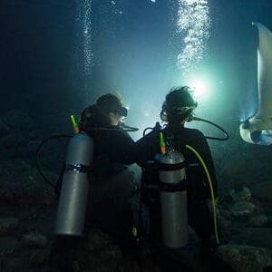 Two people in scuba gear sitting on a rock