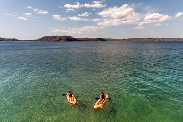 Two people are paddling on their surfboards in the water.