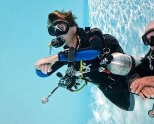 A woman in scuba gear is diving into the water.