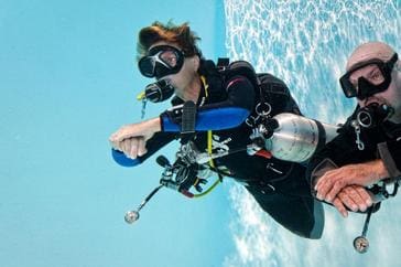 A woman in scuba gear is diving into the water.