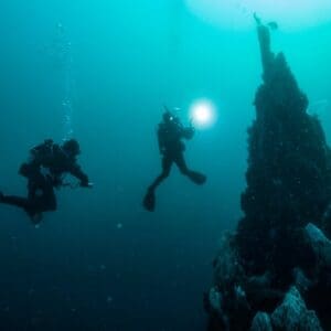 Two divers explore an underwater rock formation.