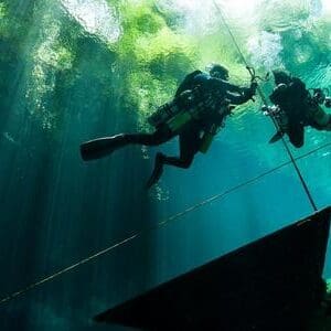 Two scuba divers in a flooded cave.