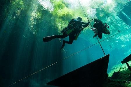 Two scuba divers in a flooded cave.