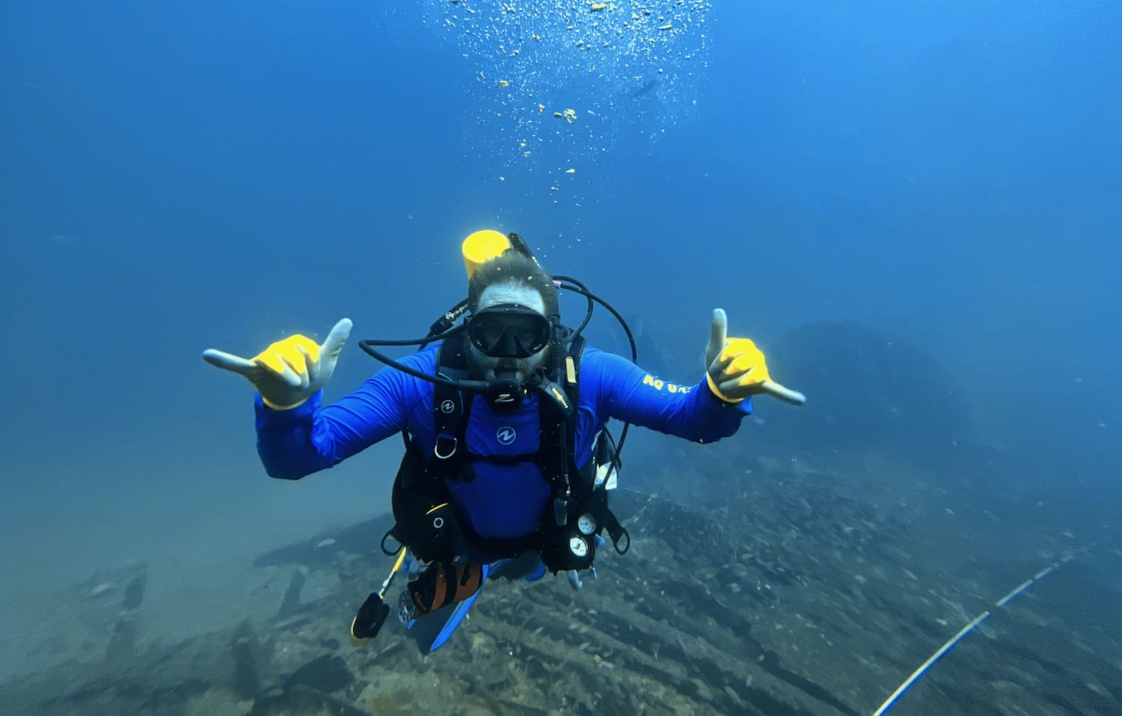 A scuba diver is pointing to the sky