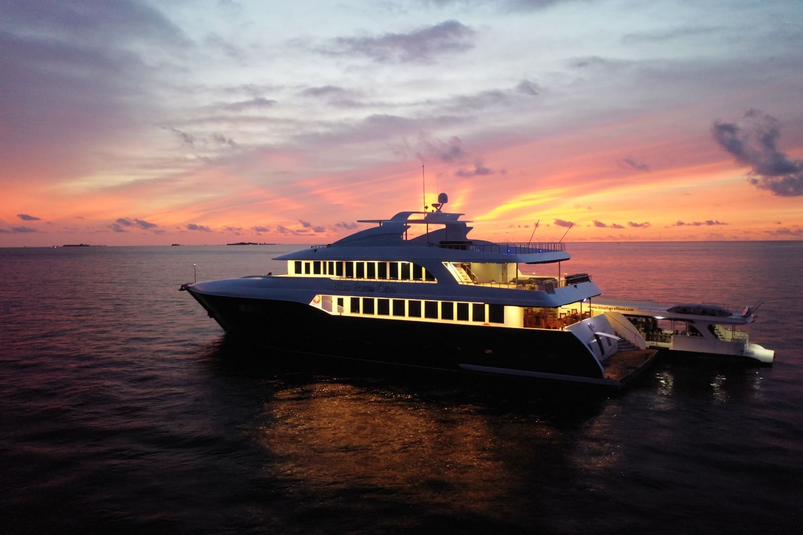 A large boat in the ocean at sunset.