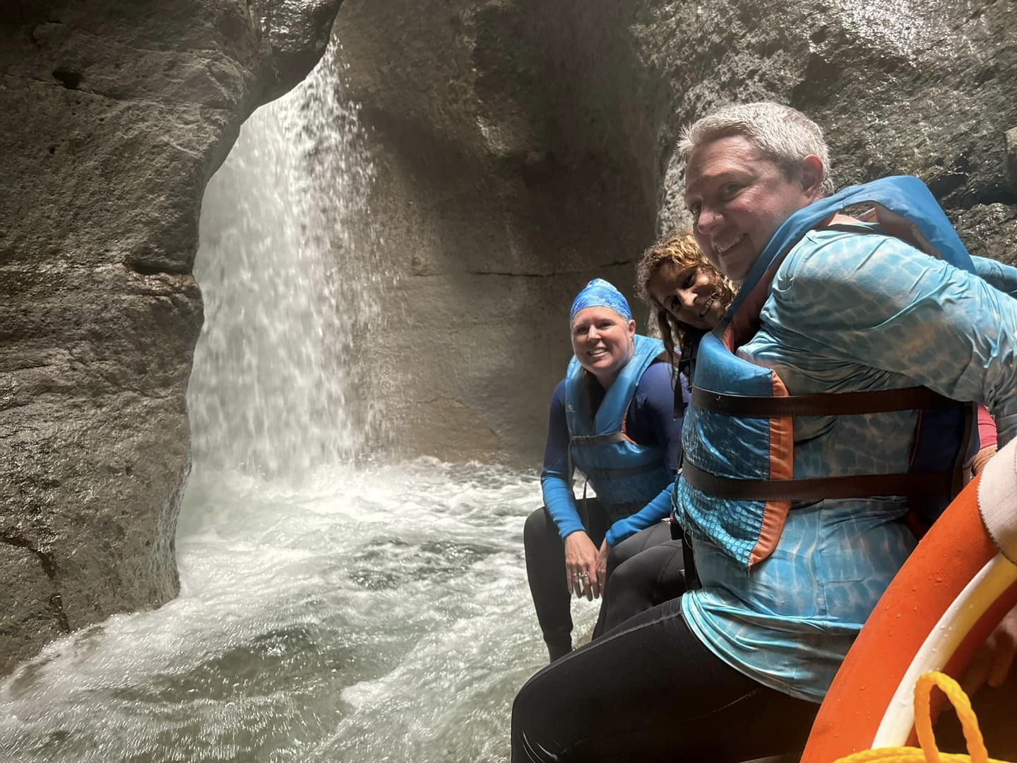 Three people by a waterfall in a cave.