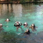 Divers swim in clear spring water.