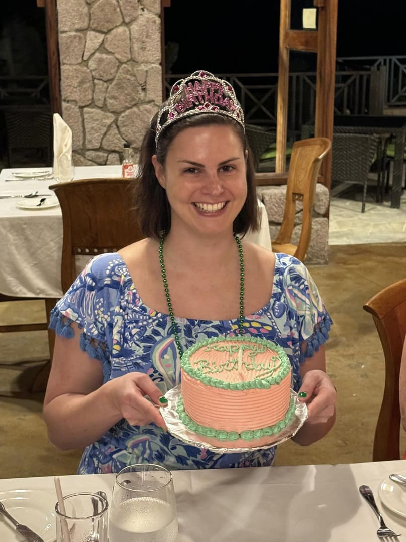 Woman wearing crown holds birthday cake.