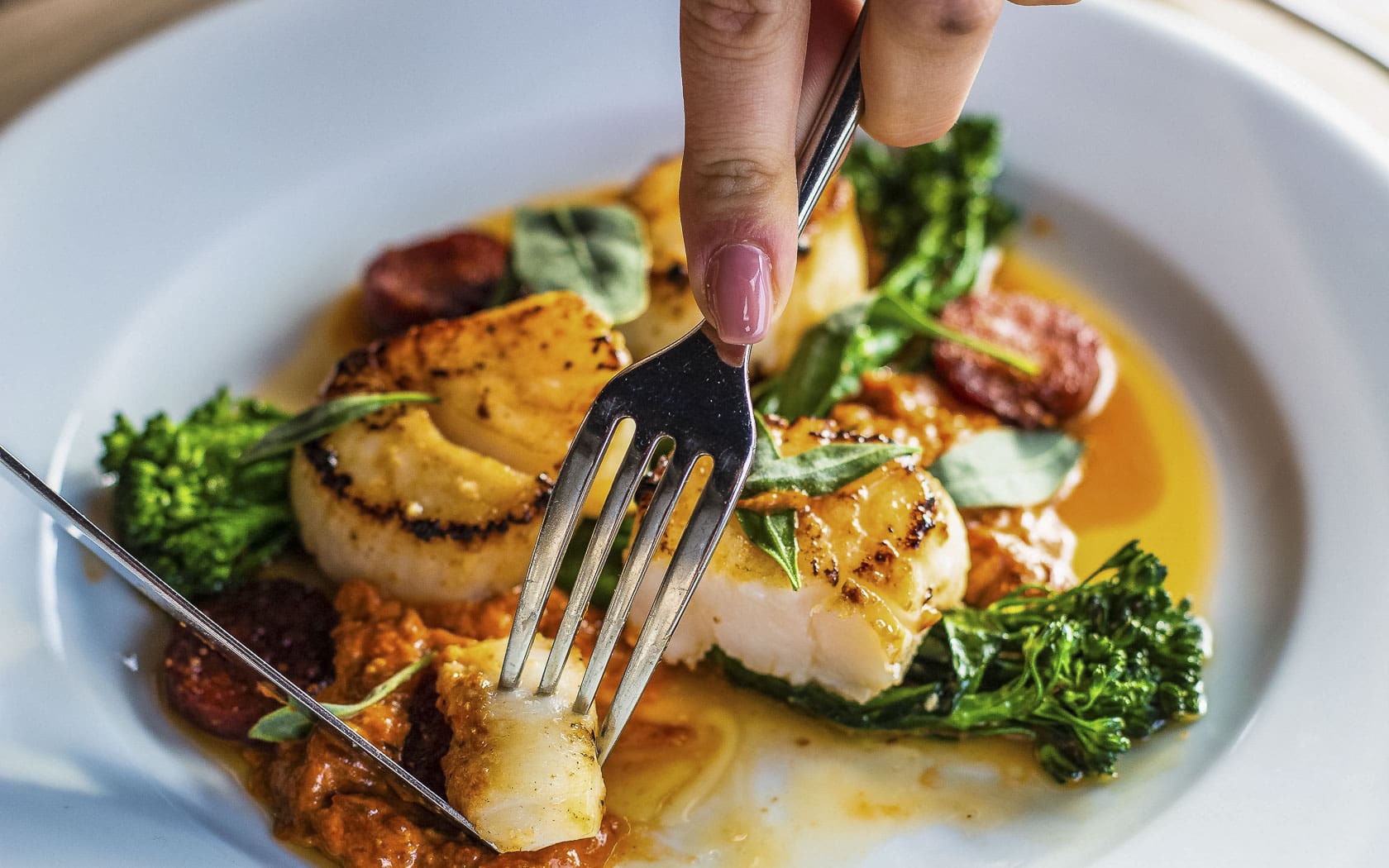 Fork lifting a seared scallop.