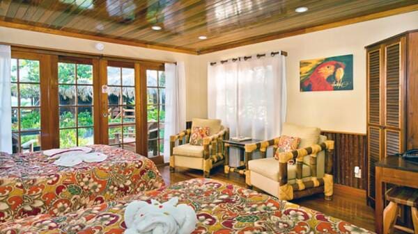 Tropical bedroom with two beds and patio views.