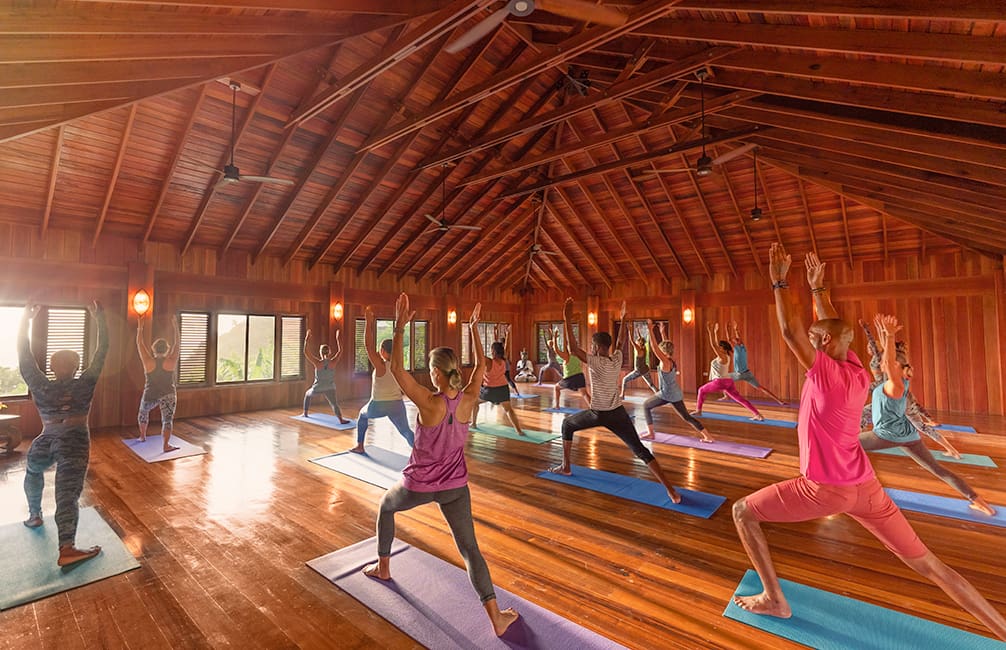 Group yoga class in a wooden room.