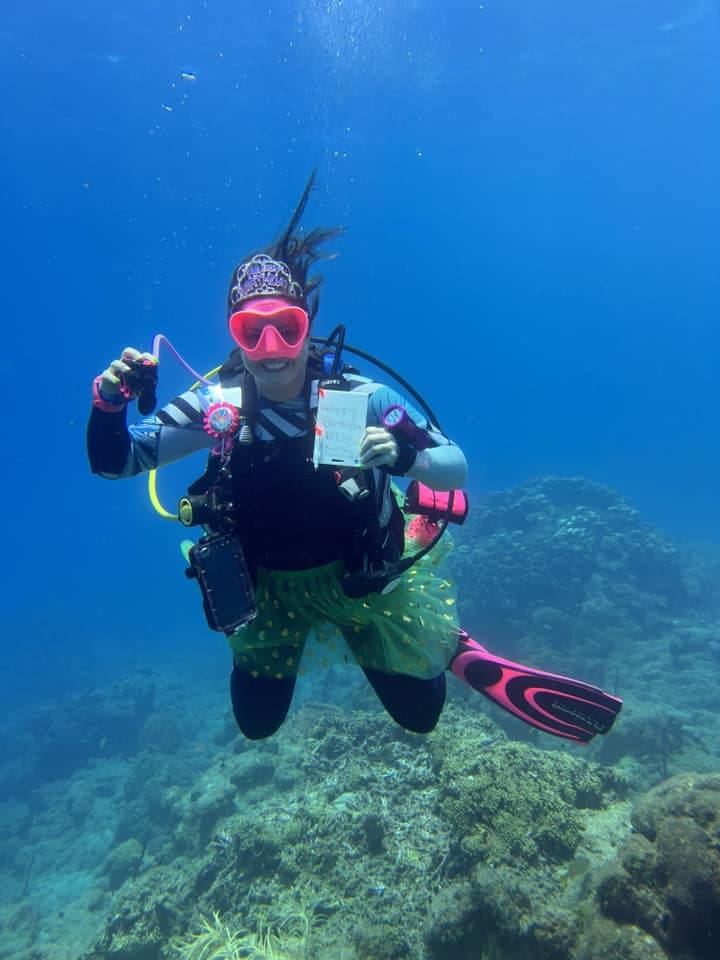 Woman scuba diving with a tiara underwater.