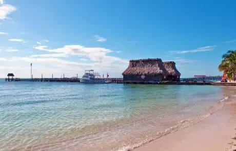 Boat docked near a thatched hut on the beach.