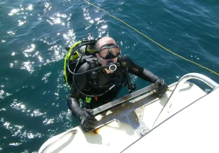 Scuba diver exiting boat in water.