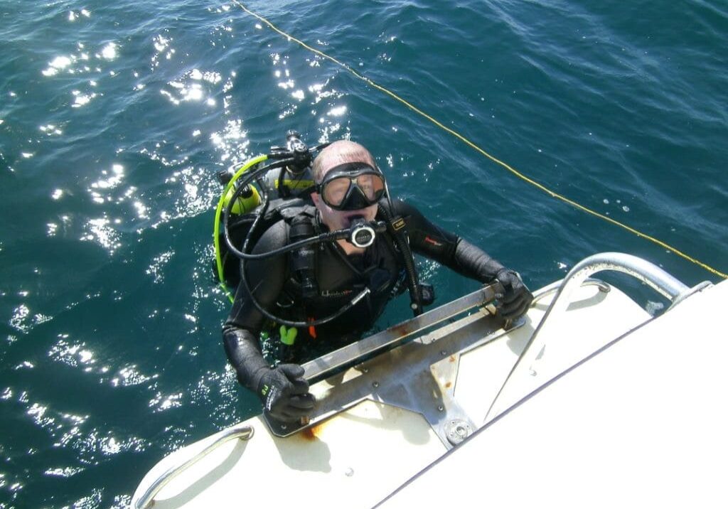 A man in scuba gear is on the side of a boat.